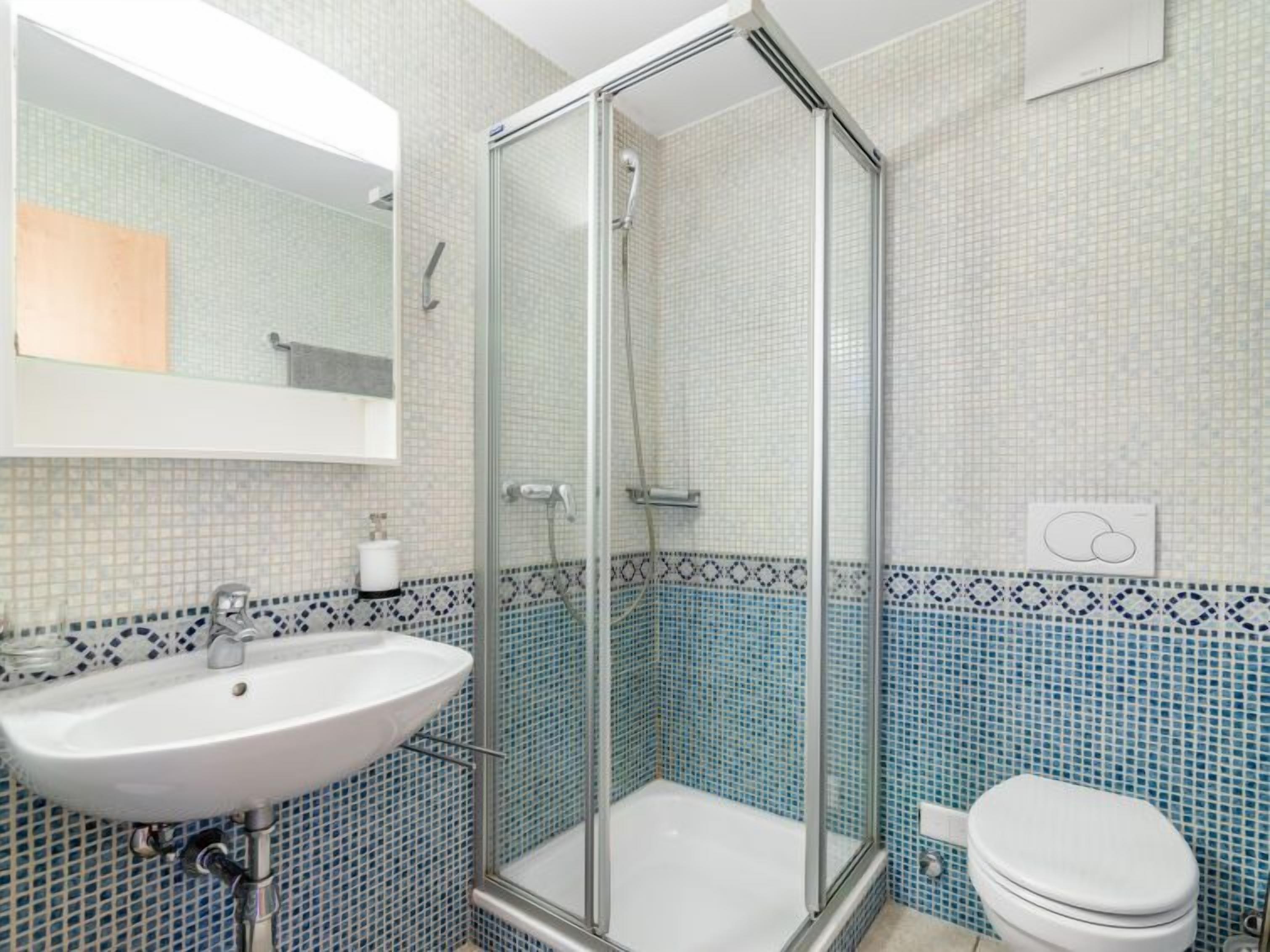 Ein Badezimmer mit einer Duschkabine, einem Waschbecken und einer Toilette.
