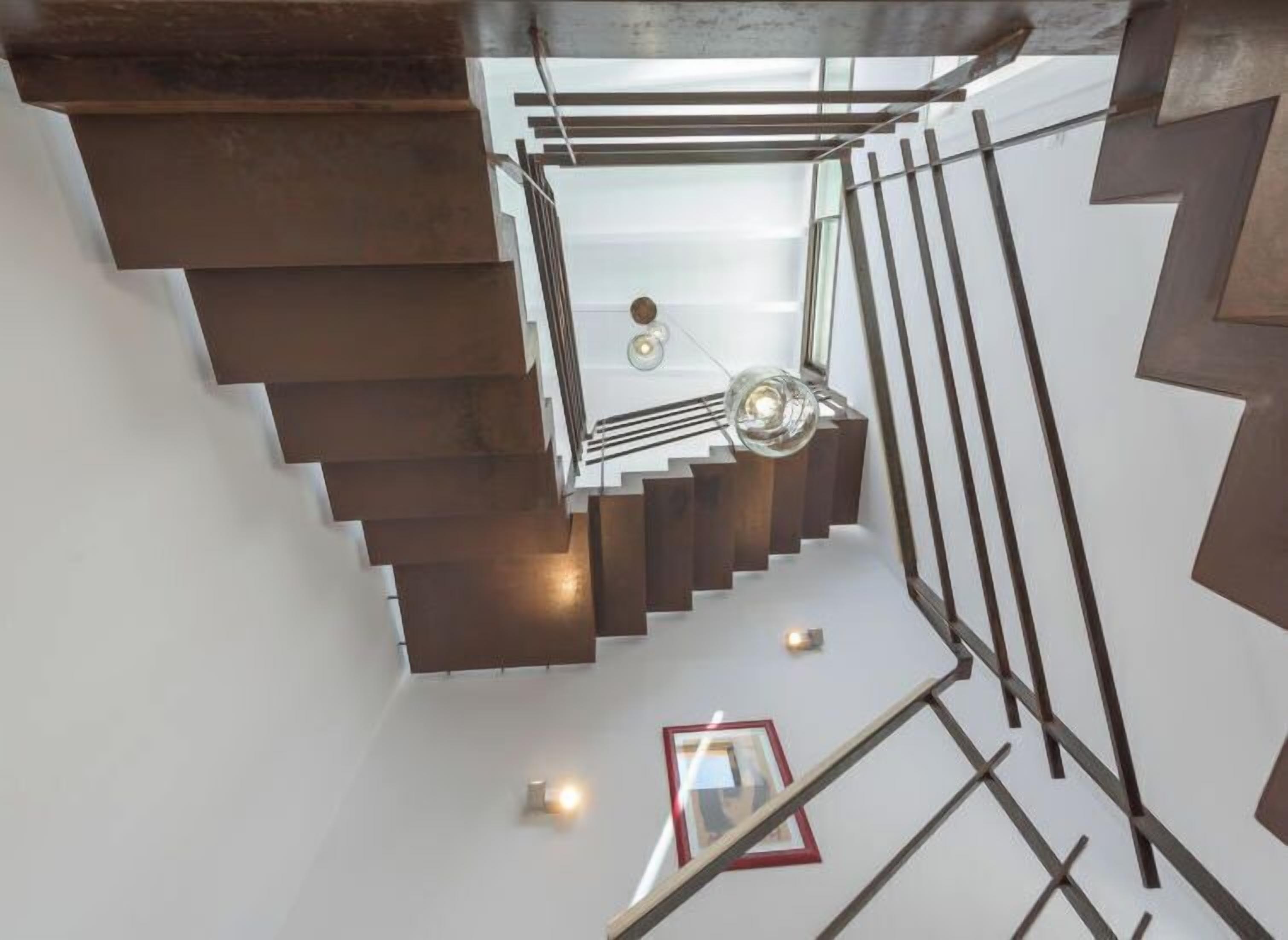 A modern staircase with a glass railing and metal accents, leading to a lower level.