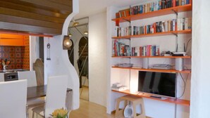 Una sala de estar moderna con comedor, una estantería y un televisor.