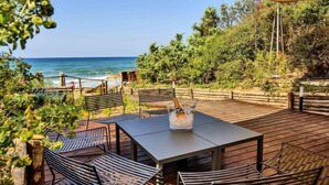 A wooden deck with a table and chairs overlooking the ocean.