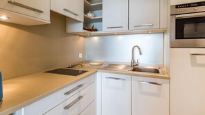 Una cocina moderna con armarios blancos, un lavamanos de acero inoxidable y un horno.