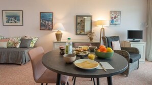 Un salón acogedor con una mesa de comedor redonda, un sofá y un televisor.