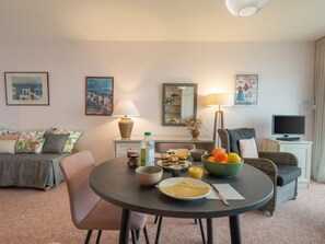 A cozy living room with a round dining table, a sofa, and a TV.