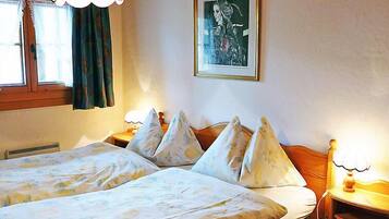Une chambre avec deux lits, une fenêtre avec des rideaux, un tableau accroché au mur et des lampes de chevet.