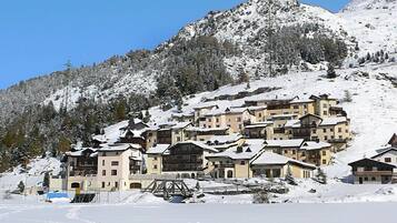 Une montagne enneigée, sur laquelle se dressent plusieurs bâtiments à étages, qui ressemble probablement à une station de ski.