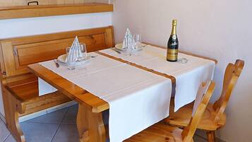 Une table à manger recouverte d’une nappe blanche, deux chaises et une bouteille de champagne.