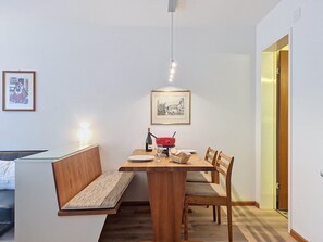 A dining area with a wooden table, bench seating, a red pot, a bottle, and a glass. - Matten (Utoring) by Interhome (Zermatt)
