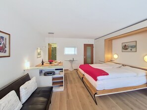 A hotel room with a bed, a desk, a chair, a small table, and a window. - Matten (Utoring) by Interhome (Zermatt)