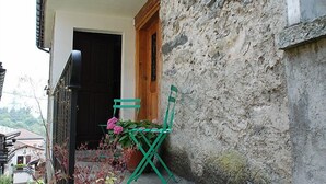 Ein Balkon mit einem grünen Stuhl und Blumentöpfen.