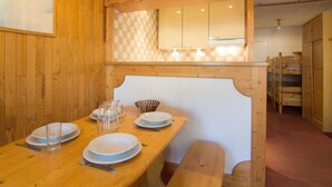 A wooden dining table with plates, glasses, and cutlery. A checkered wall pattern is visible above the table. - Le Curling B (Val Claret) by Interhome (Tignes)
