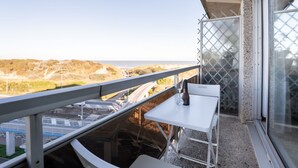A balcony with a white table and chair, overlooking a coastal landscape with hills and a road. - Studio 705 with seaview by Interhome (Bredene)