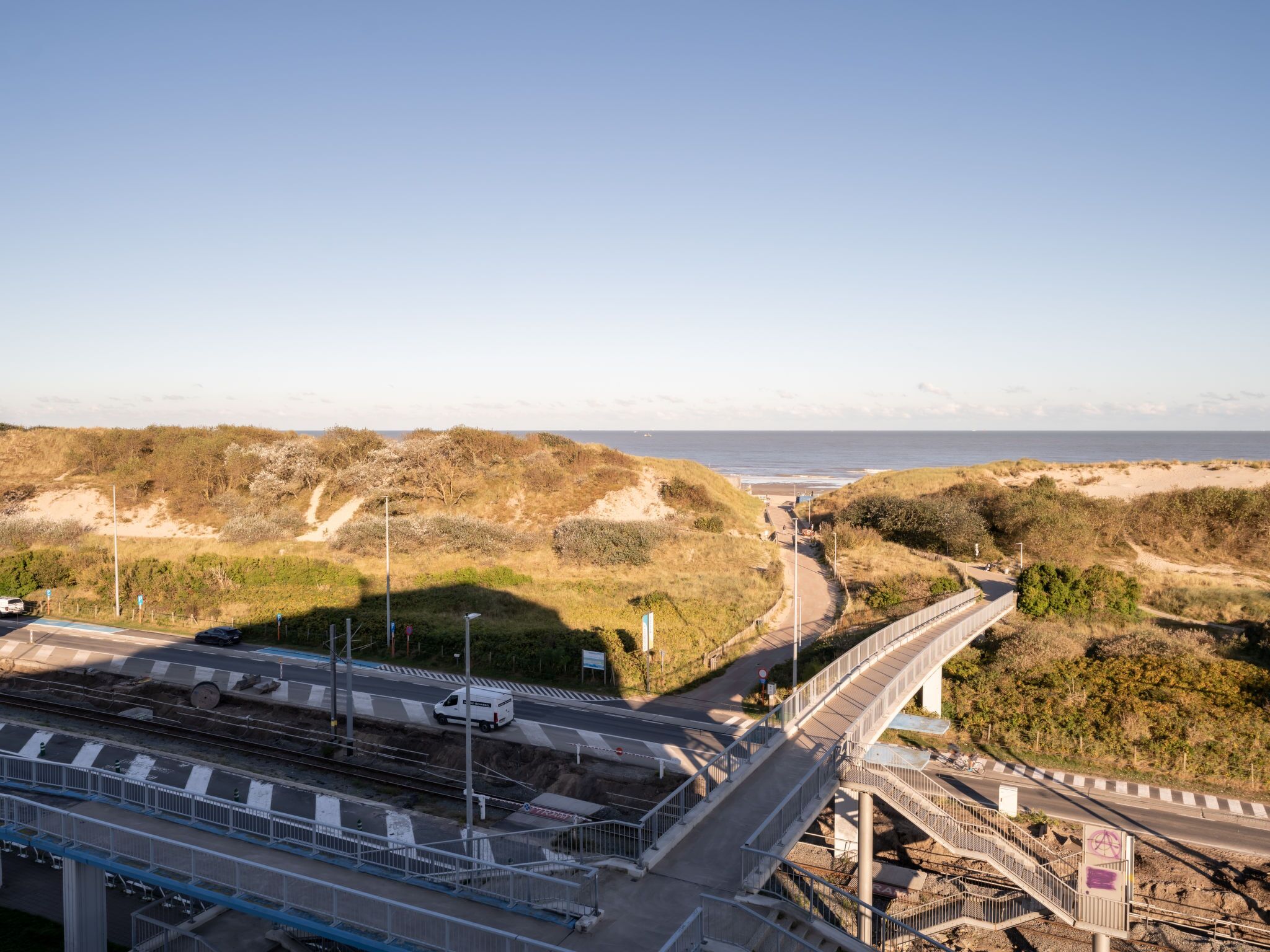 A coastal road with a bridge and railway tracks.