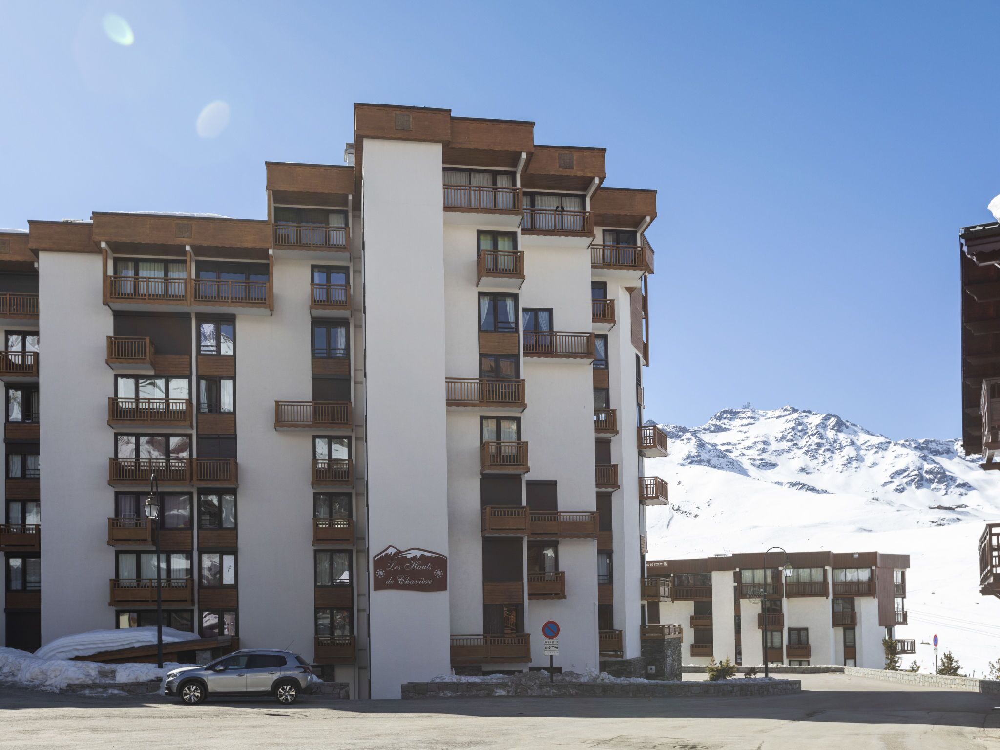 Ein mehrstöckiges Hotel mit Balkonen, einem Schild mit der Aufschrift "Les Moulins de Chavasse" und einem verschneiten Berg im Hintergrund.