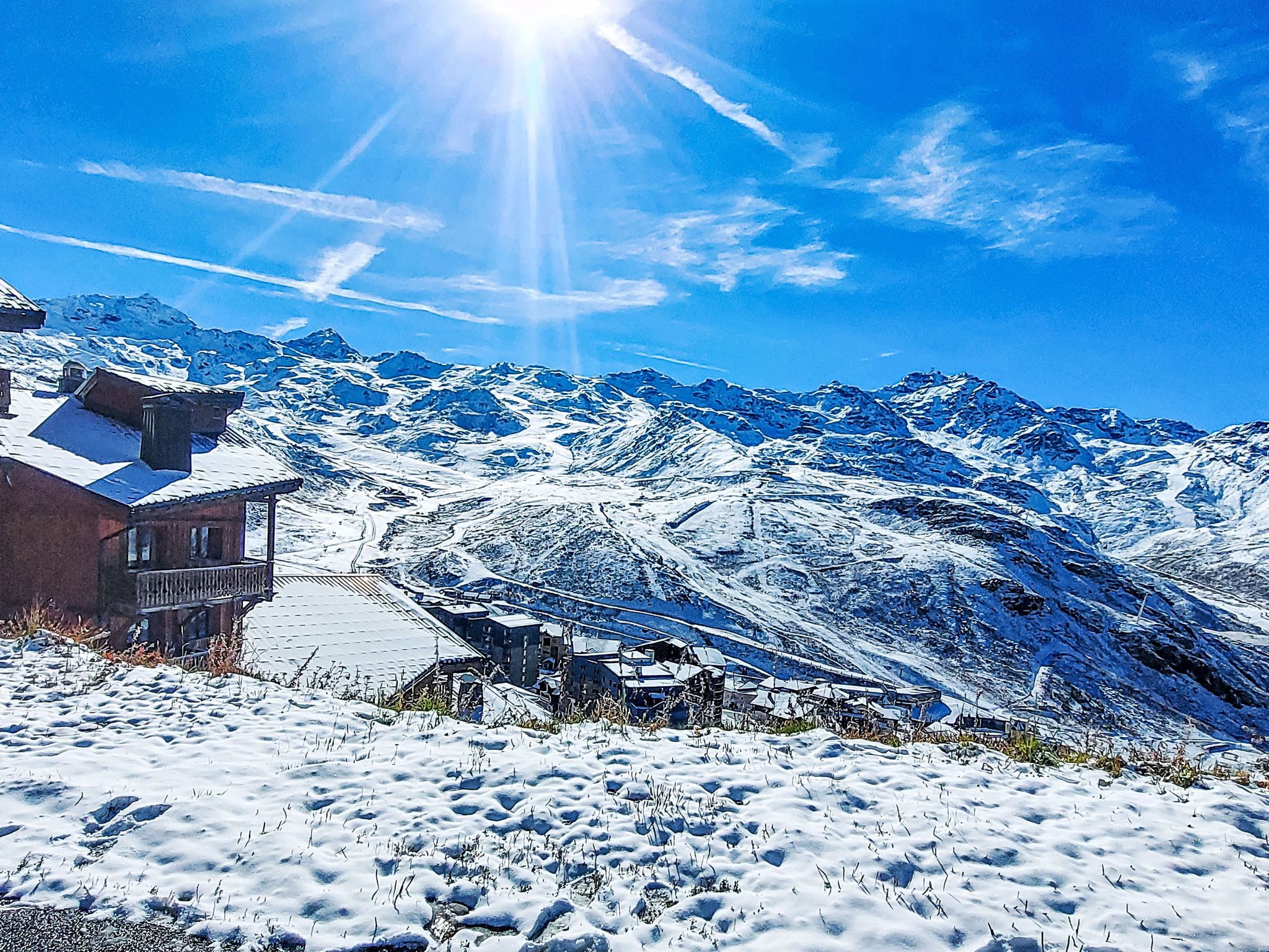 A snow-covered mountain landscape with a clear sky and a bright sun.