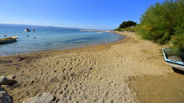 A sandy beach with a clear blue sky, a few boats, and a distant shoreline. - Apartment Niko 2 by Interhome (Omiš)