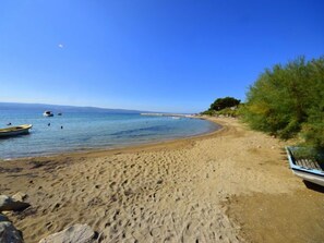 A sandy beach with a clear blue sky, a few boats, and a distant shoreline. - Apartment Niko 2 by Interhome (Omiš)