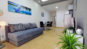 A modern living room with a sofa, a dining table, and a kitchen area with a refrigerator. - Apartment Niko 2 by Interhome (Omiš)