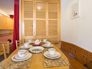 A wooden dining table set with white cups and saucers, a teapot, and a plate with a floral design. - Le Curling B (Val Claret) by Interhome (Tignes)