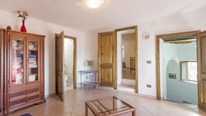 A spacious living area with a wooden cabinet, a glass coffee table, and a door leading to another room.