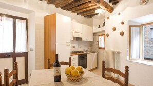 A dining area with a table set for two, a bottle of wine, and a basket of lemons.