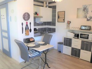 A compact kitchen with a dining table, chairs, a microwave, a toaster, and a sink.