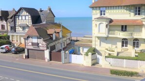 A coastal street with traditional European architecture, including a two-story building with a balcony and a corner house with a sloped roof. - Kennedy by Interhome (Villers sur mer)