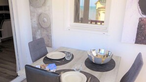 A dining area with a table set for two, including plates, cutlery, and a decorative bowl. - Kennedy by Interhome (Villers sur mer)