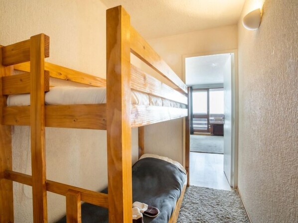 Ein Etagenbett in einem Zimmer mit Blick auf einen Balkon und einer Tür zu einem weiteren Raum.