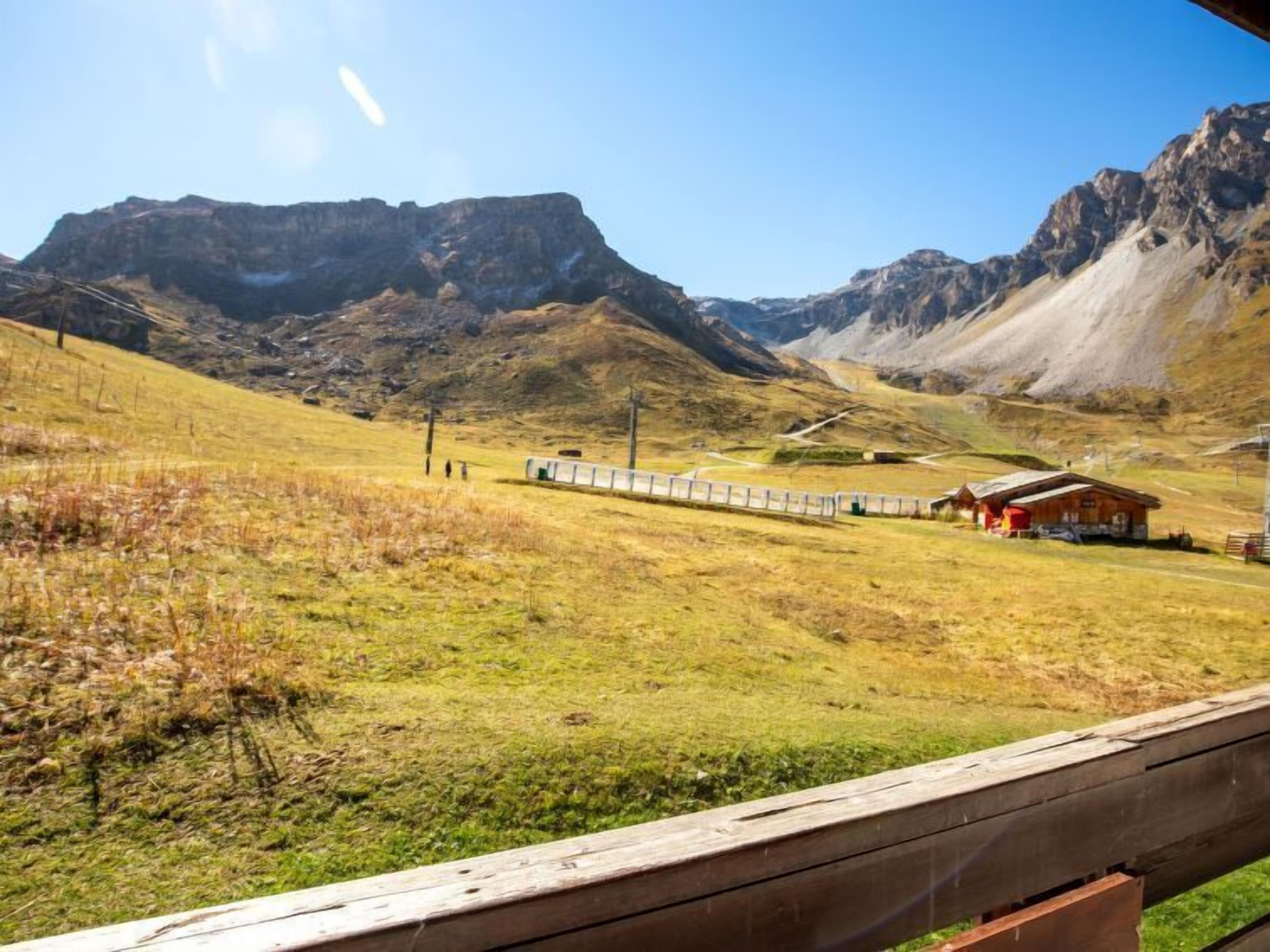 A mountainous landscape with a wooden fence, a small building, and a clear sky.