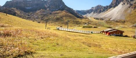 A mountainous landscape with a wooden fence, a small building, and a clear sky.