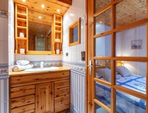 A wooden bathroom with a sink, mirror, and towel rack. - Les Tommeuses (Val Claret) by Interhome (Tignes)