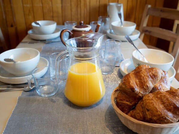 Eixugam de matí amb un lleuger d'api, plats, una teiera i croissants damunt d'una taula.