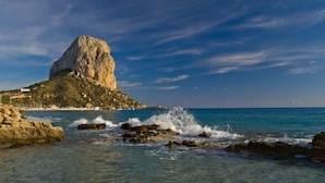 Un paysage côtier avec un promontoire rocheux imposant et des eaux d’un bleu limpide.