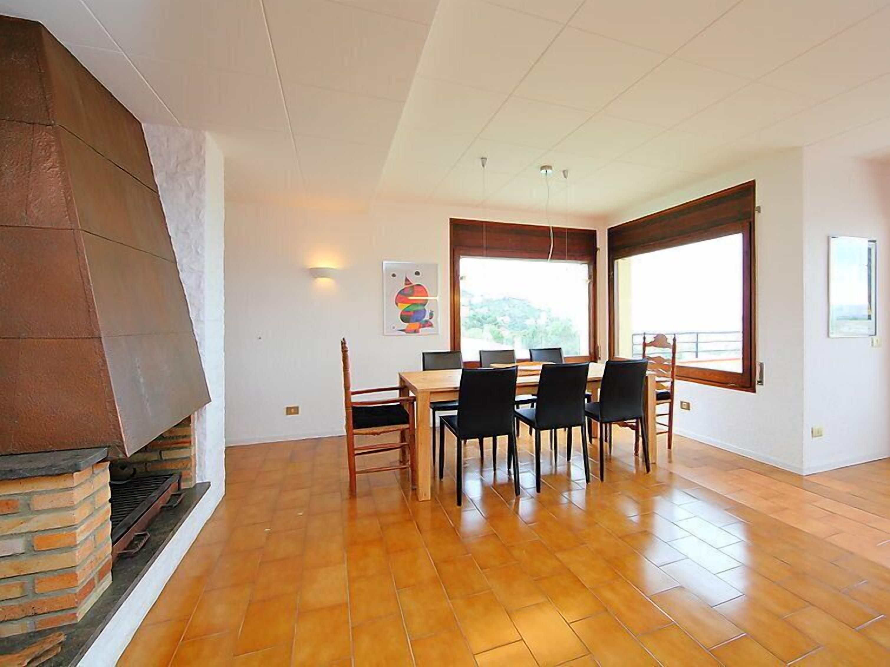 A dining area with a brick fireplace, a wooden table, and black chairs.