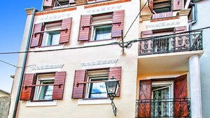 Ein mehrstöckiges Gebäude mit Holzhörnern an den Fenstern, einem Balkon mit schmiedeeisernen Geländern und einer Straßenlaterne.