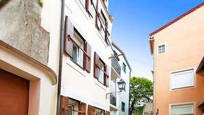Eine enge Straße mit Gebäuden an beiden Seiten, mit Balkonen und Fenstern mit Rollläden.