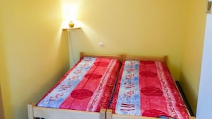 Ein kleines Zimmer mit einem Einzelbett, gelben Wänden und einer Nachttischlampe.