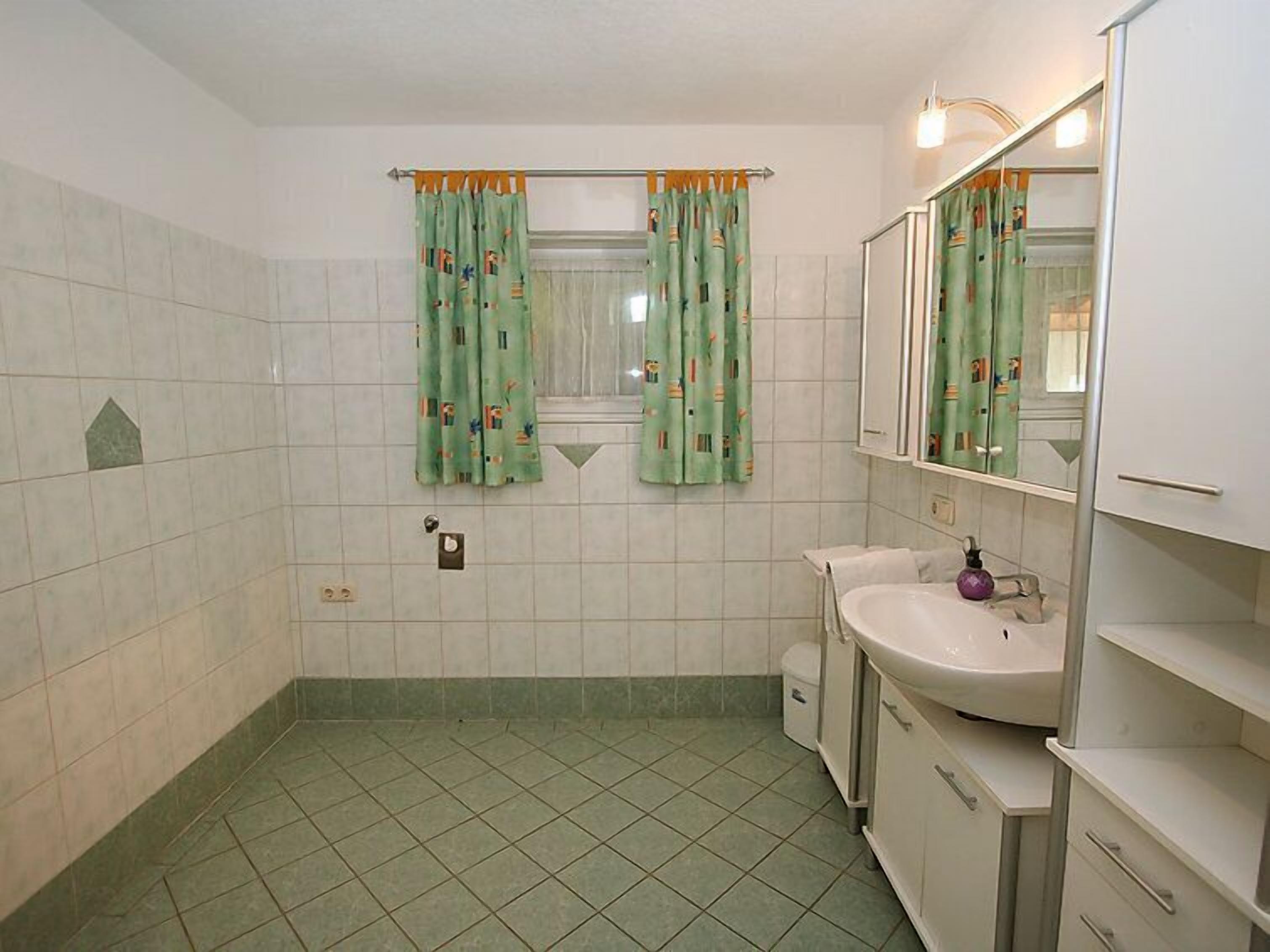 Ein Badezimmer mit Waschbecken, Spiegel und zwei Duschvorhängen.
