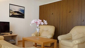 Una sala de estar moderna con una mesa de madera, dos sofás beige, un televisor y un cuadro en la pared.
