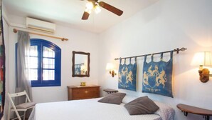 Une chambre à coucher comprenant un lit, une chaise, une commode, un miroir et deux lampes fixées au mur.