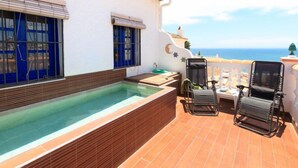 Une terrasse sur le toit avec une piscine, deux chaises longues et une vue sur l’océan.