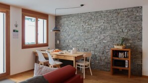 Ein Essbereich mit Steinwand, Holzmöbeln und einem kleinen Regal mit Küchenutensilien.