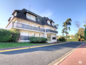 Ein zweigeschossiges Wohngebäude mit Balkon, Auffahrt und einer Straße mit Fahrradweg.