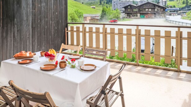 Una tavola apparecchiata per la colazione con vista su un paesaggio montuoso e edifici sullo sfondo.