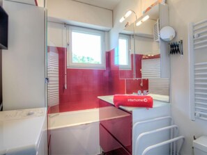 Un bagno moderno con arredamento nei toni del rosso e del bianco, un lavabo, uno specchio e una finestra.