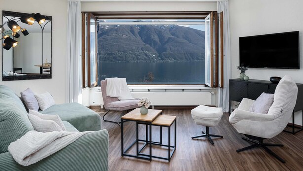 Una sala de estar moderna con un gran ventanal que ofrece vistas a la montaña, un televisor de pantalla plana y una zona de estar acogedora.