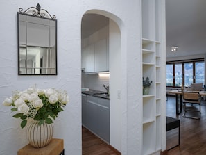 A modern kitchen with white cabinets, a large window, and a dining area with a view of the outdoors.