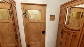 Une porte en bois avec un panneau en verre dépoli, un petit tableau encadré accroché au mur et un meuble en bois dont le dessus est incurvé.