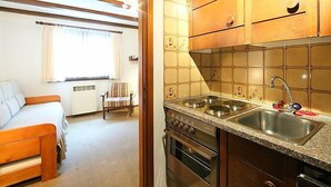 A compact kitchen with wooden cabinets, a stainless steel sink, and a built-in oven. - Residenza Chesa Margun 14-1 by Interhome (Silvaplana-Surlej)