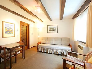 A cozy room with a wooden table, a sofa, and a bed. - Residenza Chesa Margun 14-1 by Interhome (Silvaplana-Surlej)